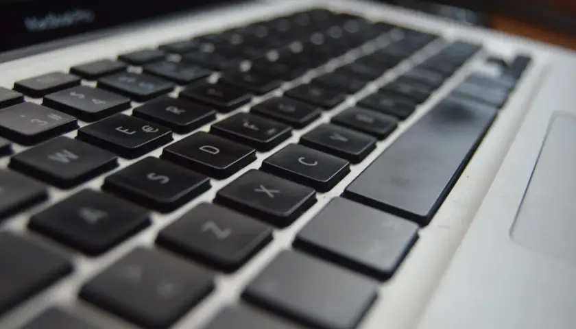 Zbliżenie na klawiaturę laptopa, widoczne klawisze z literami i cyframi. Ustawienie klawiszy jest standardowe, gotowe do pisania.