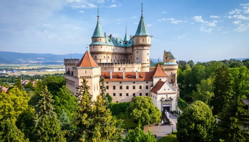 Majestatyczny zamek Bojnice, jeden z najpiękniejszych zamków na Słowacji, otoczony zielenią.