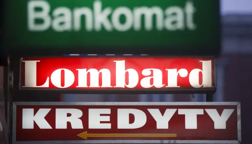 Jasny szyld "Lombard" nad napisem "KREDYTY" i niewyraźnym "Bankomat". Chcesz wiedzieć, jak otworzyć lombard?