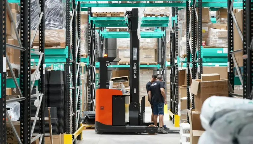 Wózek widłowy w magazynie, pracownicy przygotowują towar do wysyłki. Efektywny outbound logistics.