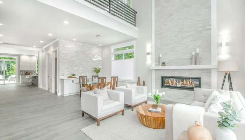 A modern living room with a fireplace, dining area, and kitchen, showcasing a full service interior design.