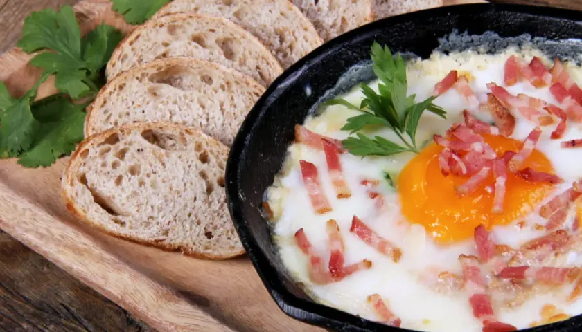 Un délicieux oeuf cocotte, parsemé de lardons croustillants, servi avec des tranches de pain de campagne.