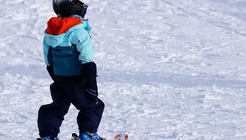 Bambino con casco, giacca e pantaloni da sci, pronto per sciare. Ecco cosa portare sulla neve per divertirsi in sicurezza!