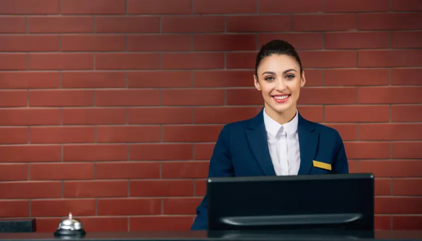Uśmiechnięta recepcjonistka w hotelu, gotowa pomóc gościom. Jej angielski jest płynny, a uśmiech serdeczny.