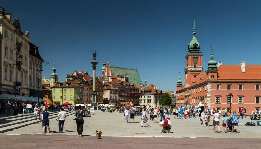 Warszawski Rynek Starego Miasta tętni życiem. Widać tu wiele zabytków w Polsce, w tym Zamek Królewski i Kolumnę Zygmunta.
