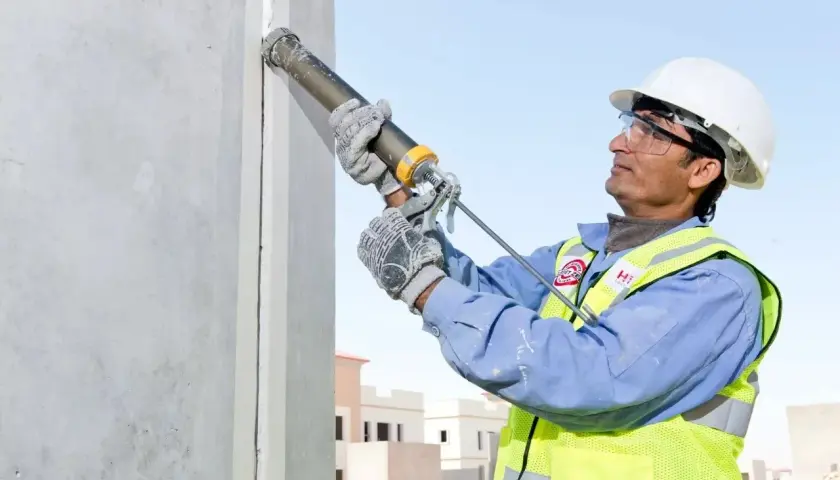 Obrero aplica Sikaflex para sellar juntas en construcción. Este adhesivo es ideal para unir y sellar materiales, asegurando durabilidad y resistencia.