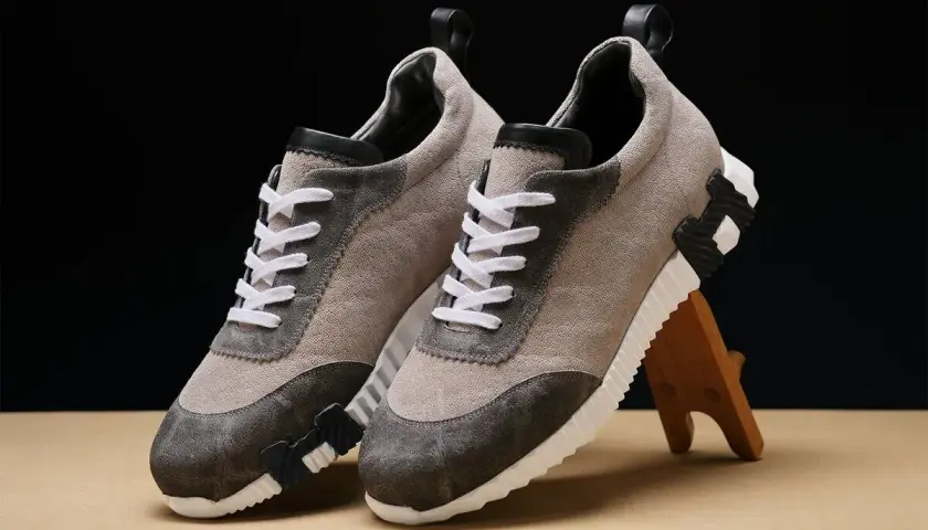 Ein Paar beigefarbene Sneaker mit grauen Akzenten und weißen Schnürsenkeln. Sie zeigen, wie orthopädische Schuhe aussehen können: stilvoll und bequem.