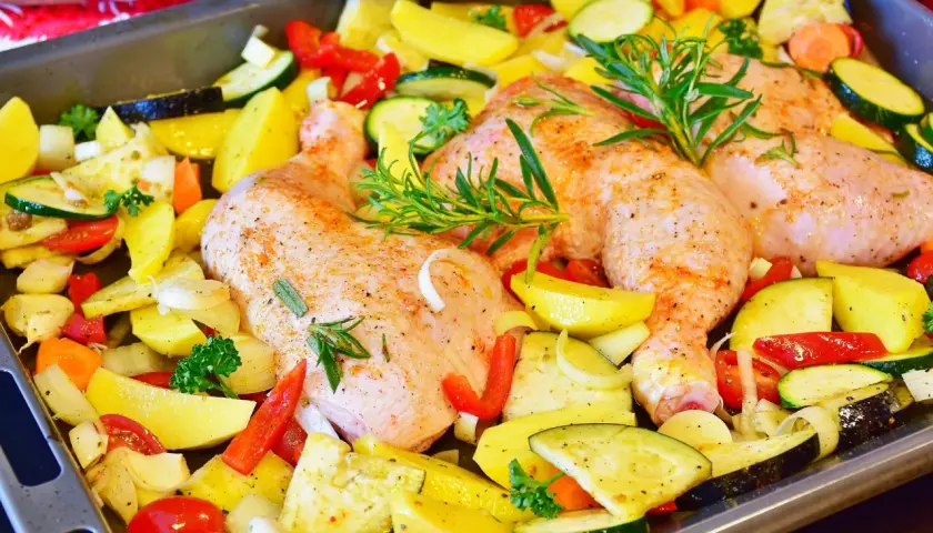 Gotowe do pieczenia: pieczone udka z kurczaka z ziemniakami, cukinią, papryką i ziołami.