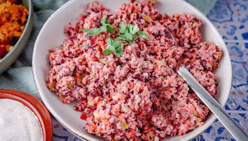 Bunter Karottensalat, frisch zubereitet im Thermomix, garniert mit Petersilie. Daneben eine Schale mit cremiger Sauce.