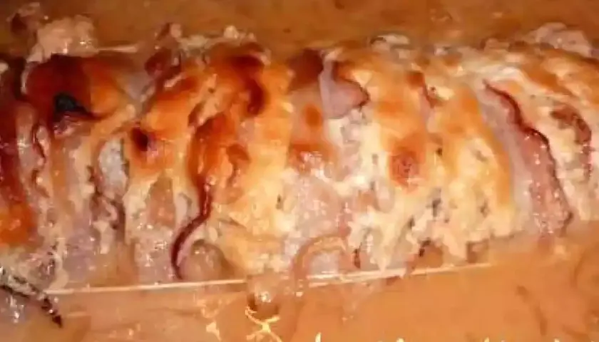 Un rôti Orloff gratiné, baignant dans une sauce onctueuse au vin blanc, prêt à être dégusté.