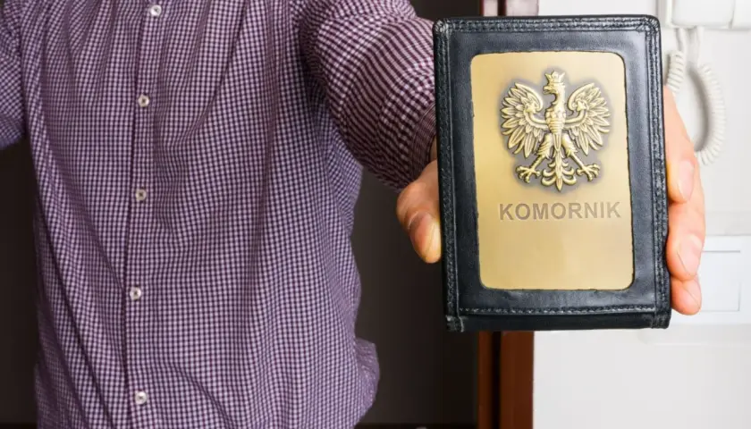Mężczyzna w koszuli prezentuje legitymację komorniczą. To znak, że może nastąpić zajęcie egzekucyjne.