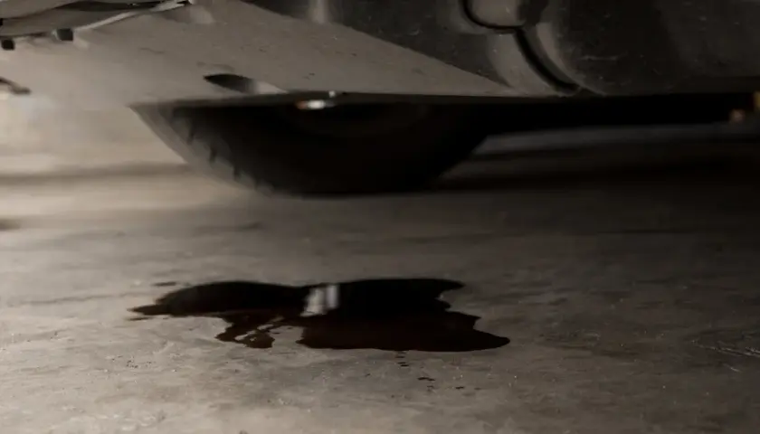Mancha de aceite en el suelo bajo un coche. ¿Cuánto costará arreglar mi coche si pierde aceite?