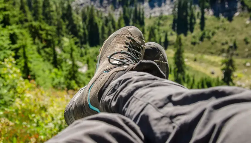 A hiker rests, their well-worn boots laced snugly. This image shows how hiking boots fit, offering comfort and support on the trail.
