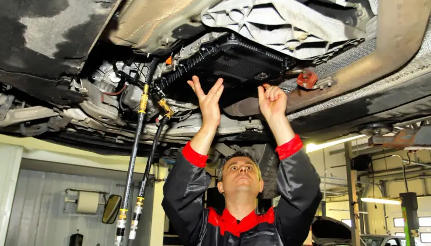 Mechanik wykonuje statyczną wymianę oleju w automatycznej skrzyni biegów, podłączając węże do układu.