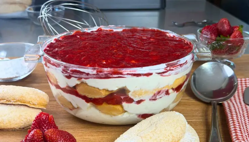 Un invitante tiramisù alle fragole in una ciotola di vetro, con savoiardi, crema e fragole fresche.
