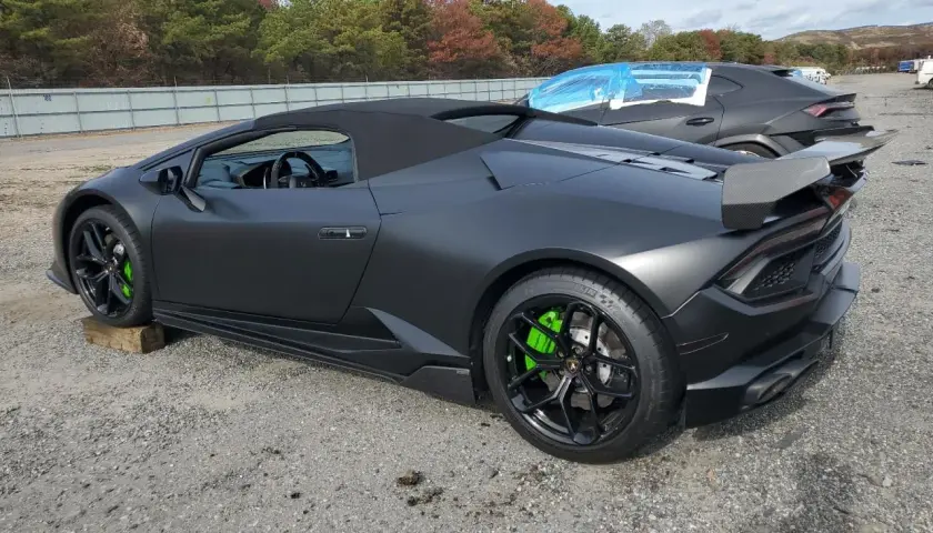 Matowy czarny lambo huracan z jaskrawozielonymi zaciskami hamulcowymi stoi na żwirowym placu.