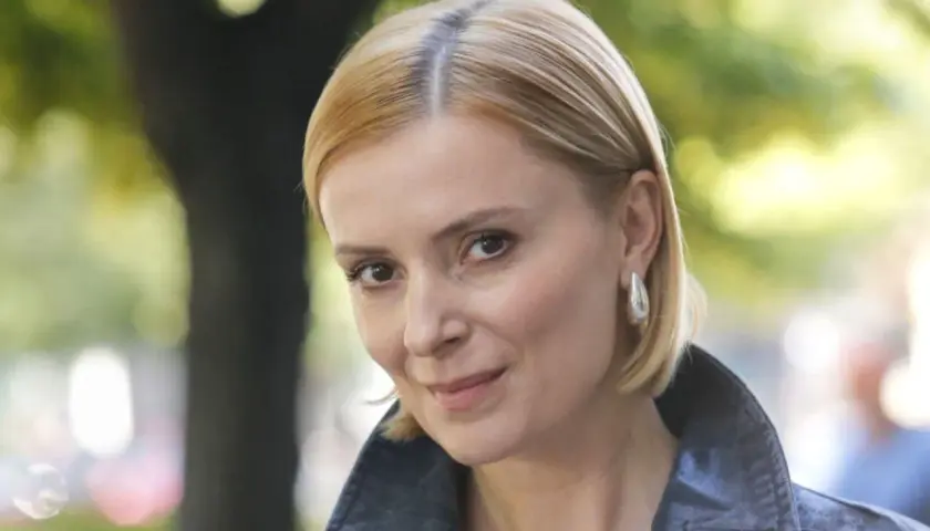 Portret Haliny Młynkowej z krótkimi blond włosami, w kurtce, na tle drzew.