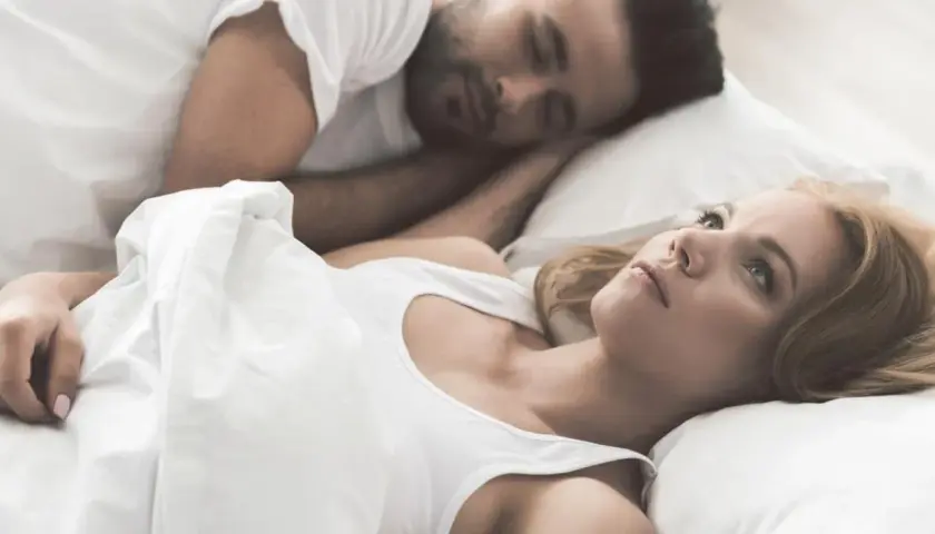 Kobieta leży obok śpiącego partnera, czując się jak sparaliżowana sennie.