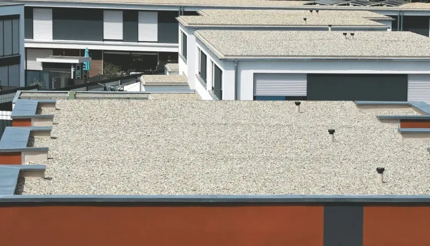 Mehrere moderne Gebäude mit verschiedenen **Flachdach Arten**, bedeckt mit Kies und mit sichtbaren Entlüftungsrohren.