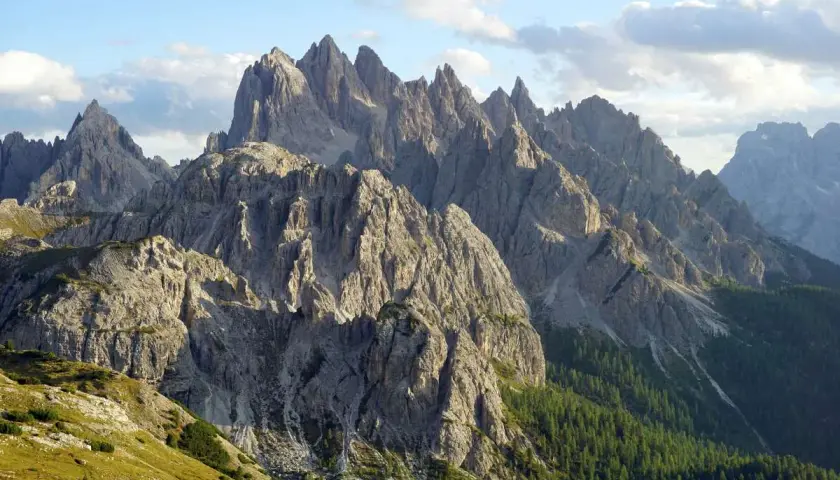 Majestatyczne szczyty Cadini di Misurina w Dolomitach, ostre jak zęby, wznoszą się ku błękitnemu niebu z chmurami.