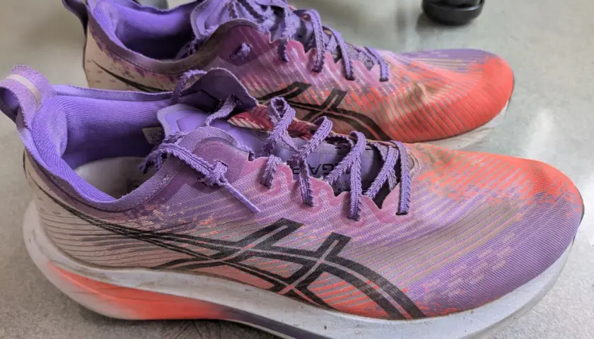 Para biegowych butów Asics Megablast w kolorze fioletowo-pomarańczowym, gotowych na kolejny trening.