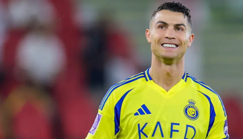Uśmiechnięty Cristiano Ronaldo w żółtej koszulce swojego nowego klubu Al Nassr.