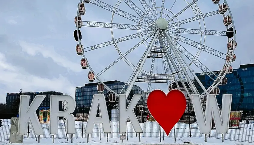 Litery "Kraków" z sercem i diabelski młyn w tle. To jedne z fajnych miejsc w Krakowie, idealne na zimowe zdjęcia.