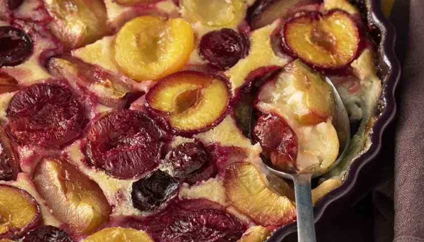 Un délicieux clafoutis aux prunes, aux couleurs vives et à la texture moelleuse, prêt à être dégusté.