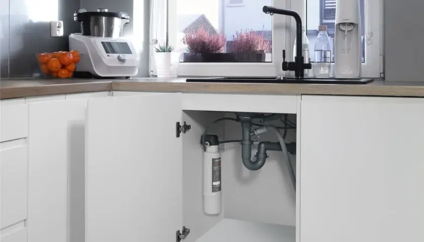 Pod zlewem widać, jak zamontować filtr do wody. Jest on podłączony do instalacji wodnej.