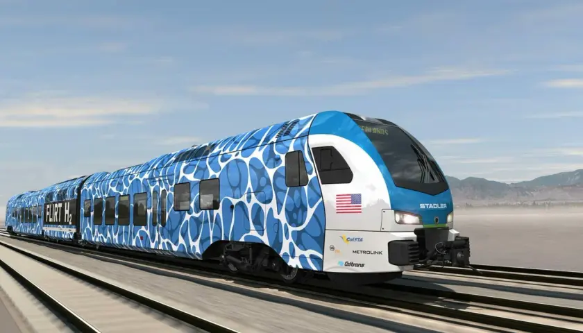 Nowoczesny pociąg Stadler FLIRT H2 z niebiesko-białym wzorem pędzi po torach.