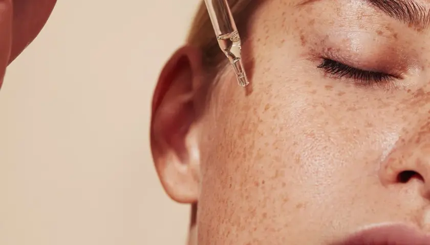 Kropla serum z pipety spada na piegowatą skórę. Dowiedz się, retinol co to i jak działa.