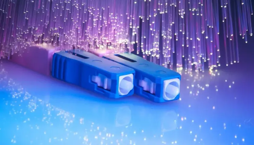 Connecteurs bleus pour télécommunication fibre optique, entourés de fils lumineux violets.