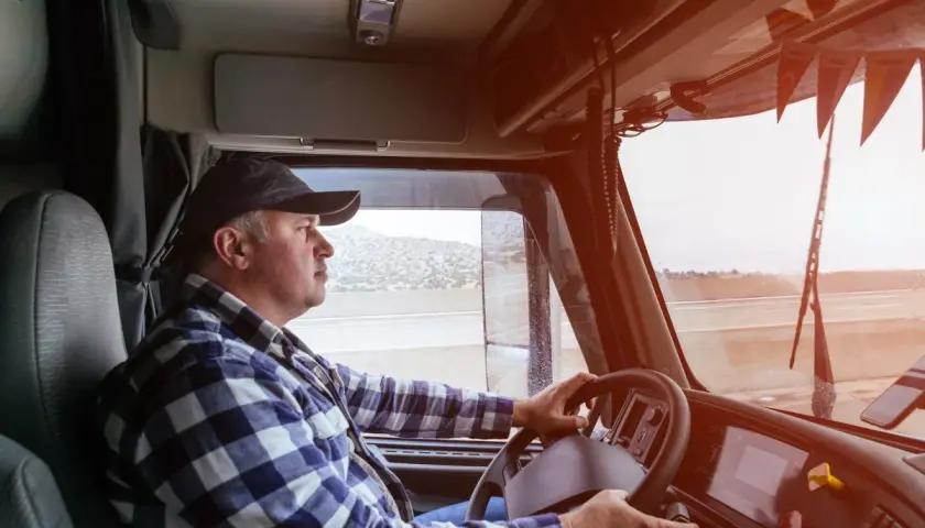 Ein LKW-Fahrer im karierten Hemd lenkt seinen Truck. Sein Gehalt ist ein wichtiger Faktor für seine Arbeit.