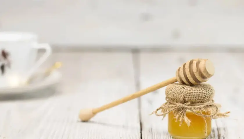 Słodki miód w słoiczku z drewnianą chochlą. Zastanawiasz się, ile kcal ma łyżeczka miodu?