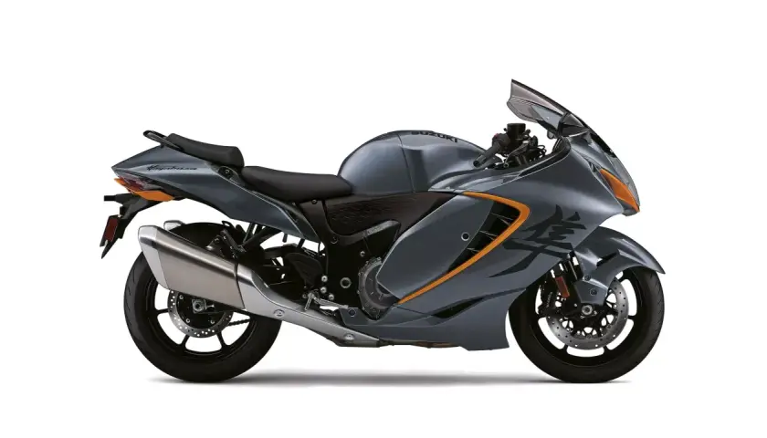 Motocicleta Suzuki Hayabusa gris con detalles naranjas, lista para la velocidad. Su diseño aerodinámico sugiere potencia, como si tuviera un turbo oculto.
