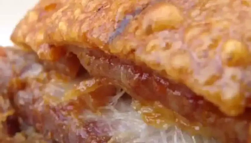Gros plan sur un délicieux lard rôti au four, la couenne croustillante et dorée, la chair tendre et juteuse. Un vrai régal !