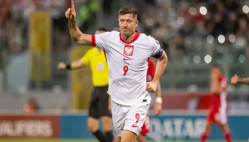 Robert Lewandowski, jeden z najlepszych polskich piłkarzy, świętuje bramkę. Jego biała koszulka z orłem i numerem 9 to symbol dumy narodowej.