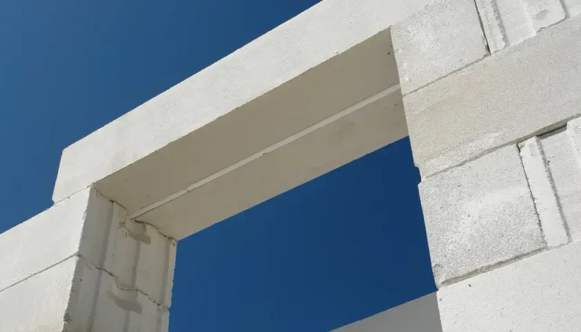 Białe nadproże nad drzwiami 80, wykonane z bloczków z betonu komórkowego, na tle błękitnego nieba.