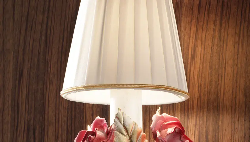 Elegancka lampka nocna z plisowanym abażurem i ceramicznymi różami u podstawy.