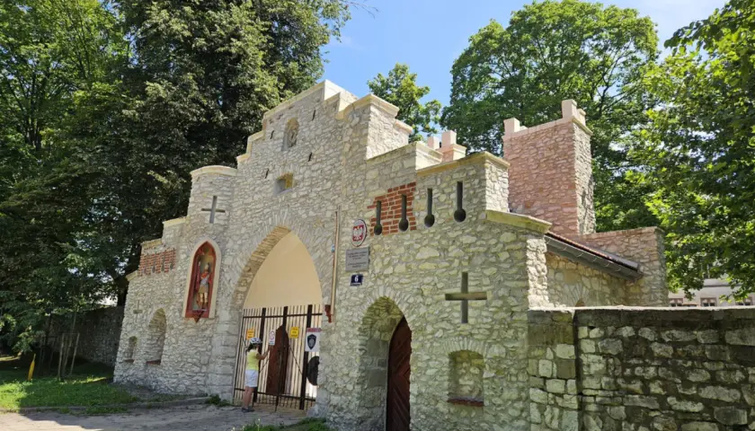 Kamienna brama z krzyżami i figurą świętego, przypominająca wejście do puszczy dulowskiej.
