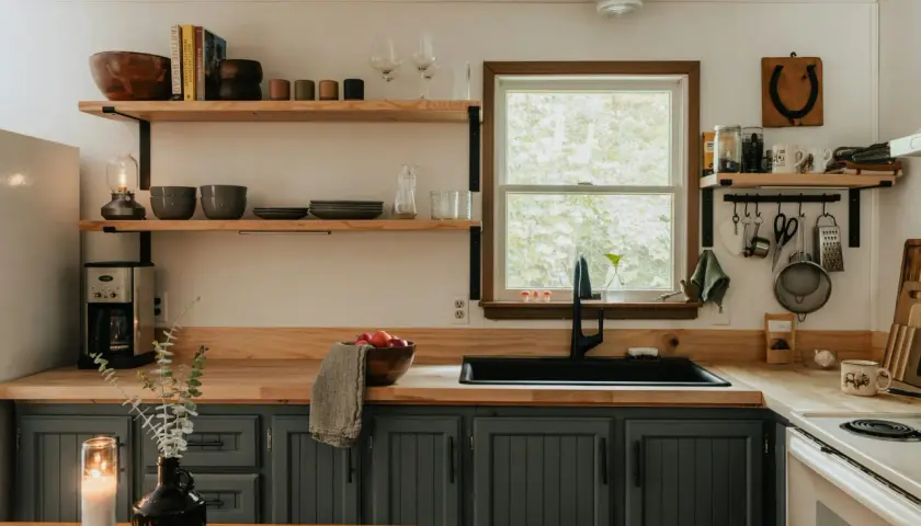Cozy kitchen with dark gray cabinets, wooden countertops, and open shelving, perfect for an affordable kitchen makeover.