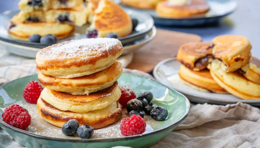 Fluffige Buttermilch Pancakes, bestäubt mit Puderzucker und garniert mit frischen Beeren. Ein Genuss für jeden Morgen!