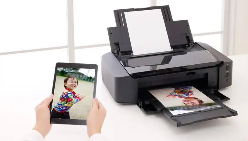 Drukarka atramentowa drukuje zdjęcie dziecka z tabletu. Wybór odpowiedni jaki papier fotograficzny do drukarki atramentowej zapewni najlepszą jakość.
