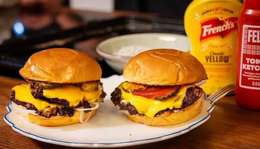 Två saftiga hamburgare med smält ost, pickles och lök. Perfekt för ett gott hamburgare recept.