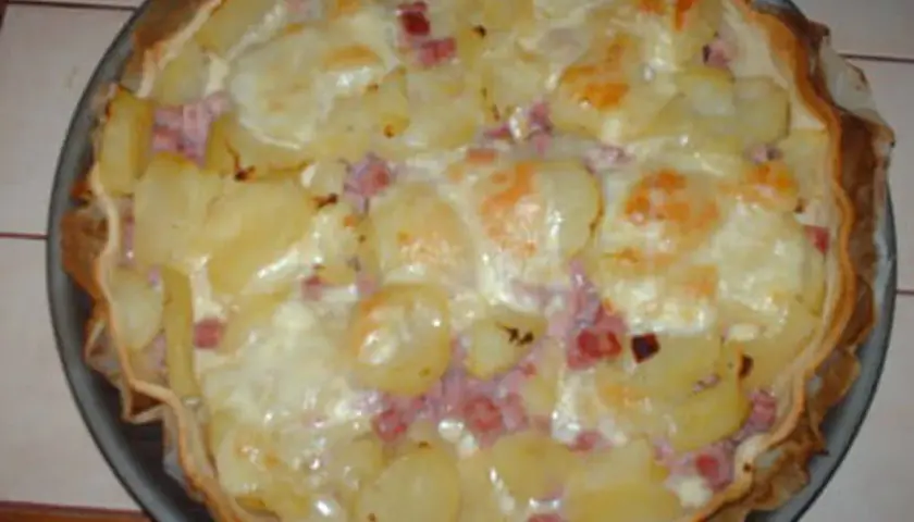 Tarte façon raclette, garnie de pommes de terre, lardons et fromage fondant. Un délice réconfortant !