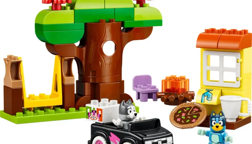 Bluey und Bingo spielen mit LEGO DUPLO im Wald. Ein Baumhaus, ein Auto und eine kleine Hütte sind aufgebaut.