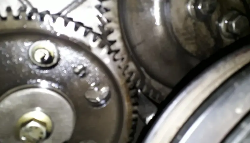Zbliżenie na mechanizm zębatek, kluczowe dla ustawienia pompy wtryskowej Perkins 4. Widoczne śruby i smar.
