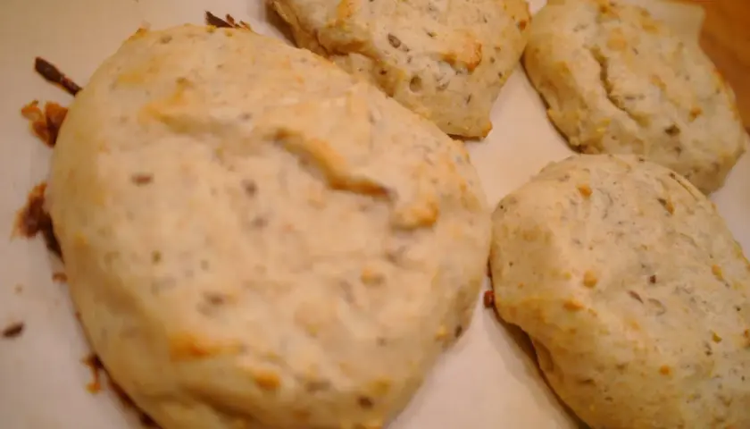 Nybakade bullar med bakpulver, fulla av frön, ligger på ett bakplåtspapper.