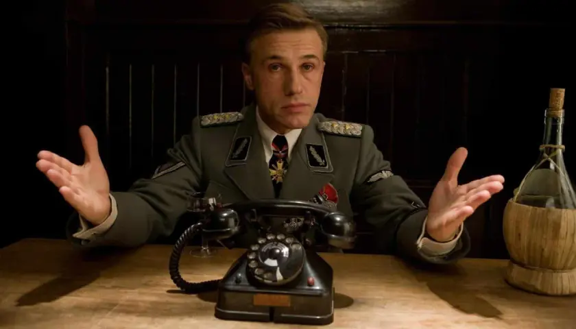 Colonnello Hans Landa, in uniforme, con le mani aperte, in una scena di "Bastardi senza gloria".
