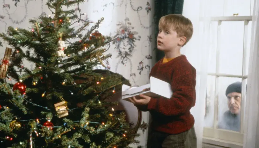 Kevin, protagonista di "Mamma, ho perso l'aereo", guarda sorpreso un intruso fuori dalla finestra, vicino all'albero di Natale.